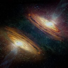 Două galaxii, în nuanțe de portocaliu, pe fundal negru. Galaxia canibală care își „devorează” vecinii a fost descoperită recent