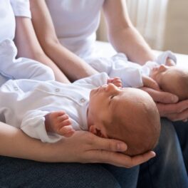 Părinți îmbrăcați în alb, care țin în brațe gemeni identici, una dintre cele mai rare nașteri din lume